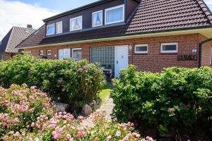 een huis met struiken en bloemen ervoor bij Pension Luuward 3 Sterne superior Hotel in Wenningstedt