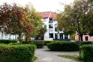 un edificio con árboles y arbustos frente a un edificio en HOTELOVÉ UBYTOVÁNÍ U RADNICE en Valašské Klobouky