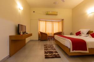 a hotel room with a bed and a television at KSTDC Hotel Mayura Sangama Mekedatu in Mulhalli