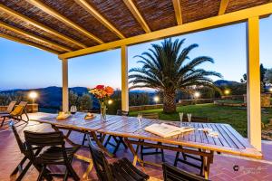 una mesa de madera con sillas en un patio con una palmera en Bio Fattoria Il Poggiarello, en Volterra