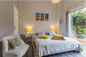 a bedroom with a bed and a chair and a window at LES PIEDS DANS L'EAU in Merville-Franceville-Plage
