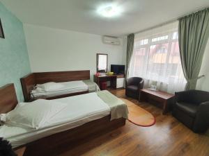 - une chambre avec deux lits, une chaise et une fenêtre dans l'établissement Moldotour, à Iaşi