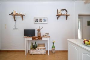 a kitchen with a table with a tv on a wall at KATINA COTTAGE in Kontogiannátika