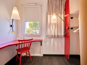 Cette chambre comprend un bureau rouge et une chaise rouge. dans l'établissement ibis La Roche Sur Yon Vendespace, à Mouilleron-le-Captif
