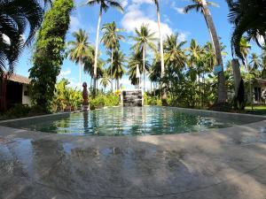 una persona in piedi di fronte a una piscina con palme di Asian Secret Resort a Lamai Beach