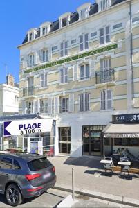 une voiture garée devant un grand bâtiment dans l'établissement Résidence de la plage, à Trouville-sur-Mer