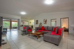 a living room with a couch and red pillows at Shades of Nature in Marloth Park