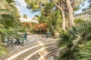 a patio with a table and chairs and palm trees at Villa Prestige '50 in Capri +30 photos