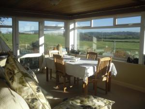 a dining room with a table and chairs and windows at Parc Yr Odyn in Pentraeth