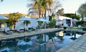 a pool with chairs and tables and umbrellas at Swartberg Hotel, Cork Tree Collection in Prince Albert