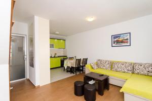 a living room with a yellow couch and a kitchen at Holiday Home Jasenka Trstenik in Trstenik