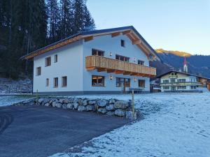 a large white house with a balcony in the snow at Appartement Bergfuier in Holzgau