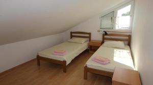 2 łóżka w małym pokoju z oknem w obiekcie Apartments Ravlic w mieście Malinska
