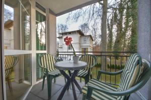 a table with chairs and a vase with a flower on a balcony at Villen am Buchenpark 08 in Heringsdorf