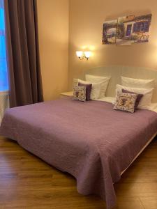 a bedroom with a large bed with purple sheets and pillows at Гоголь Апарт in Saint Petersburg