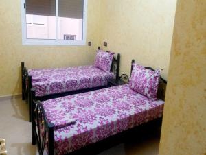 - 2 lits avec des couvertures violettes dans une chambre dans l'établissement Yasmine Appartements, à Temara