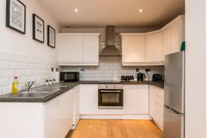 uma cozinha com armários brancos e um frigorífico de aço inoxidável em Host & Stay - Exchange Quarters em Liverpool