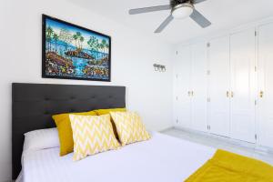a bedroom with a bed with yellow pillows and a ceiling fan at Villa Privada Mirador de La Gomera con jacuzzi in Puerto de Santiago