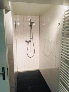 a shower with a hose in a white tiled bathroom at ruhiges privates Zimmer in Freiburg, zentrumsnah, Nähe Europapark in Freiburg im Breisgau