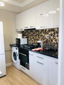 a kitchen with white cabinets and a washer and dryer at The Classic Studio in Buzău
