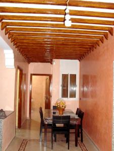 comedor con techo de madera, mesa y sillas en Yasmine Appartements, en Temara