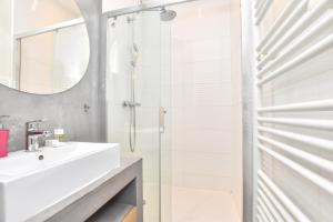 een witte badkamer met een wastafel en een douche bij CMG Résidence Réaumur in Parijs +42 foto's