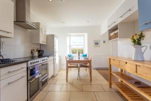 a kitchen with white cabinets and a table in it at East Linton 4 Bedroom Cottage in East Linton
