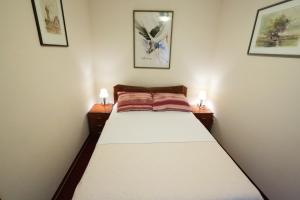 a small bedroom with a bed with two night stands at Apartments & Rooms Vienna in Osijek