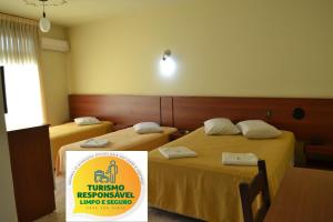 twee bedden in een kamer met een bord ervoor bij Hotel Scala in Porto Alegre