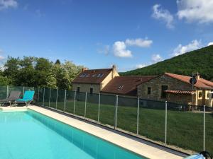 a fence around a swimming pool in front of a house at Cottage de La Mothe in Marnac