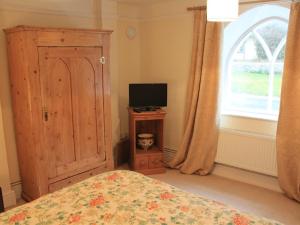 1 dormitorio con 1 cama, TV y ventana en Church Farmhouse B & B en Kennett