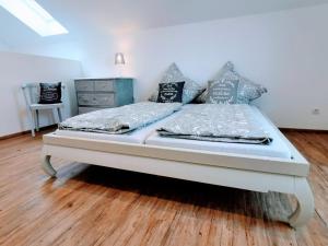 ein weißes Bett in einem Schlafzimmer mit Holzboden in der Unterkunft Marie Antoinette in Schwandorf in Bayern