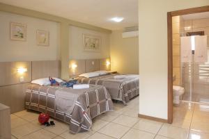 a hotel room with two beds and a shower at Pousada Floratta Nossa Casa in Gramado