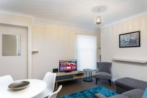 uma sala de estar com uma televisão e uma mesa e cadeiras em Cosy Stay Swansea - TV in every bedroom em Swansea