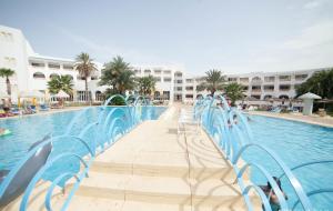 a swimming pool with blue chairs next to a resort at Hotel Liberty Resort in Monastir