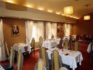 uma sala de jantar com mesas e cadeiras com toalha de mesa branca em Harty Costello Town House em Ballybunion