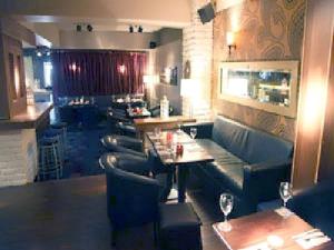 um restaurante com um bar com mesas e cadeiras em Harty Costello Town House em Ballybunion