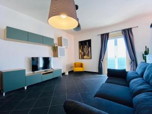 een woonkamer met een blauwe bank en een tv bij Sea View Apartment 5 mt from the beach in Salerno
