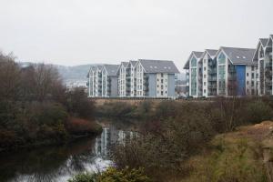 a row of apartment buildings next to a river at Royal Sovereign with Parking - TV in every Bedroom! in Swansea