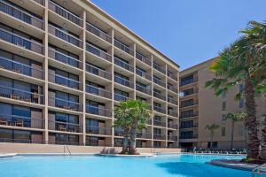 a large apartment building with a swimming pool and palm trees at Wyndham Garden Fort Walton Beach Destin in Fort Walton Beach