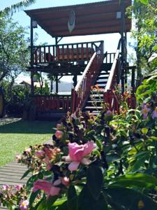 a wooden deck with stairs and flowers in a garden at Morada Vista da Lagoa in Garopaba