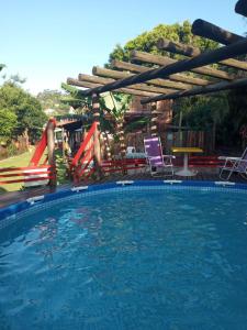 a swimming pool with a slide and a playground at Morada Vista da Lagoa in Garopaba