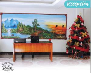 un arbre de Noël à côté d'un bureau avec un tableau dans l'établissement Hospedaje Dulce Despertar, à Sogamoso