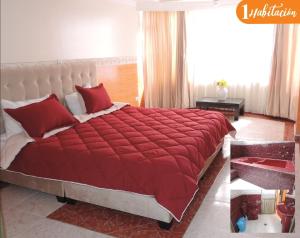 ein Schlafzimmer mit einem großen Bett mit einer roten Bettdecke in der Unterkunft Hospedaje Dulce Despertar in Sogamoso