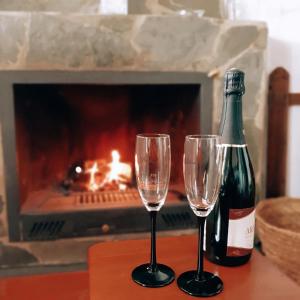 two wine glasses and a bottle on a table in front of a fireplace at Apartamentos Rurales Sierra Alta in Benaocaz