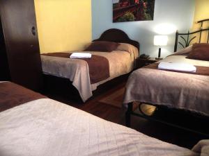 a room with three beds in a hotel room at La Merced Plaza Hostal in Riobamba
