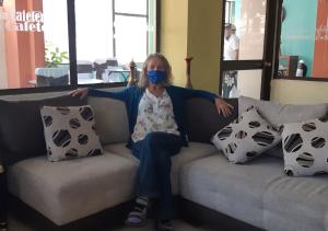 uma mulher sentada num sofá usando uma máscara em La Merced Plaza Hostal em Riobamba