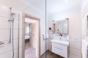 a white bathroom with a sink and a mirror at Hotel Garni ELISABETH in Pörtschach am Wörthersee