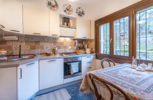 a kitchen with white cabinets and a table with a table cloth at Hladik House - Alpi Giulie Cosy Apartment in Tarvisio