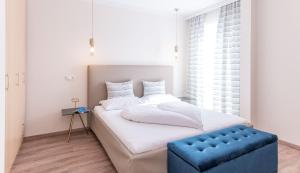 sypialnia z białym łóżkiem i niebieskim stołkiem w obiekcie Hotel Garni ELISABETH w mieście Pörtschach am Wörthersee